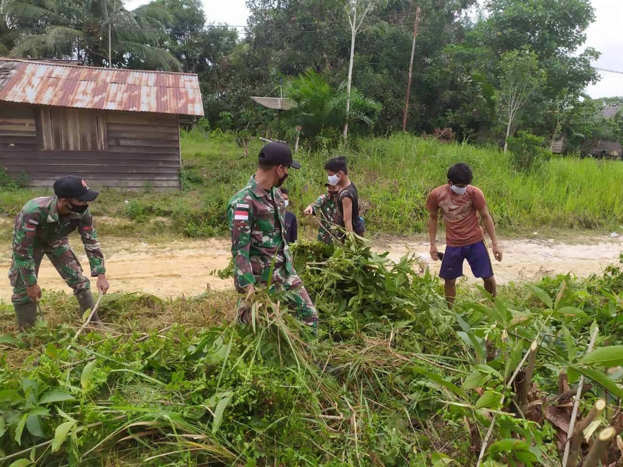 Pelihara Nilai Gotong Royong, Satgas Yonif 144/JY Bersama Warga Bersihkan Jalan Desa