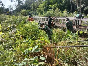 Anggota Satgas Yonif 144/JY Gotong Royong Bersihkan Jalan Desa Bersama Warga Perbatasan