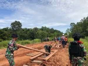 Personel Satgas Yonif 757/GV Gotong Royong Perbaiki Jalan Rusak