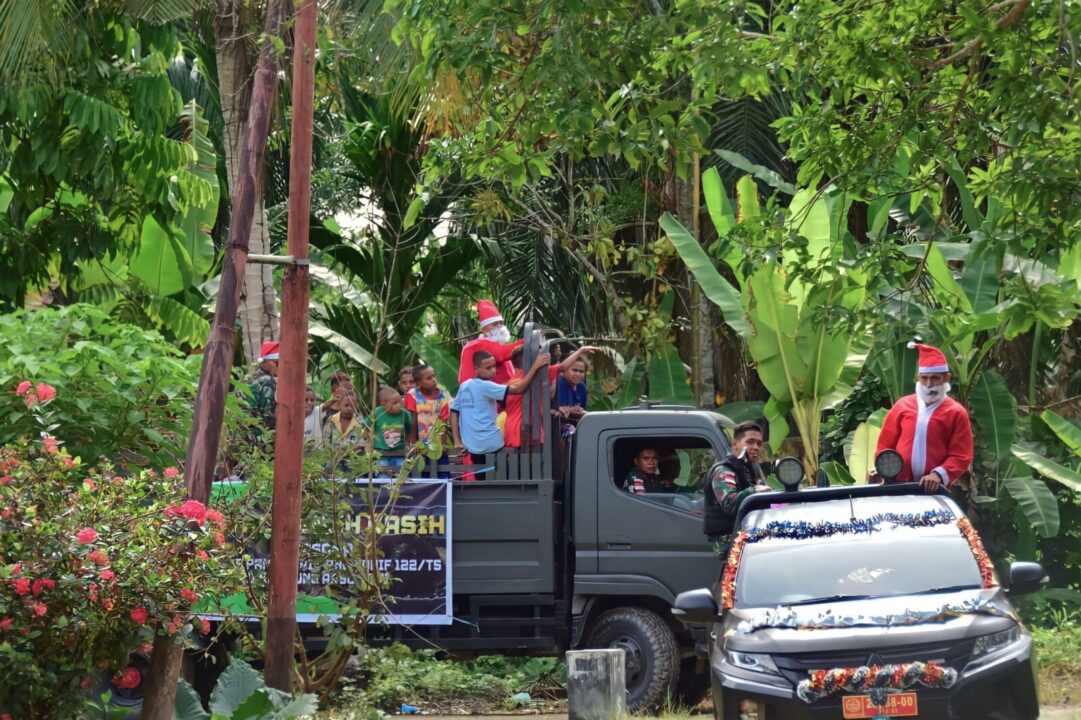 Satgas Yonif 122/TS Hadirkan Santa Claus dengan membagikan bingkisan makanan pada Karnaval menyambut perayaan Hari Raya Natal Penuh Kebahagiaan dan Kedamaian